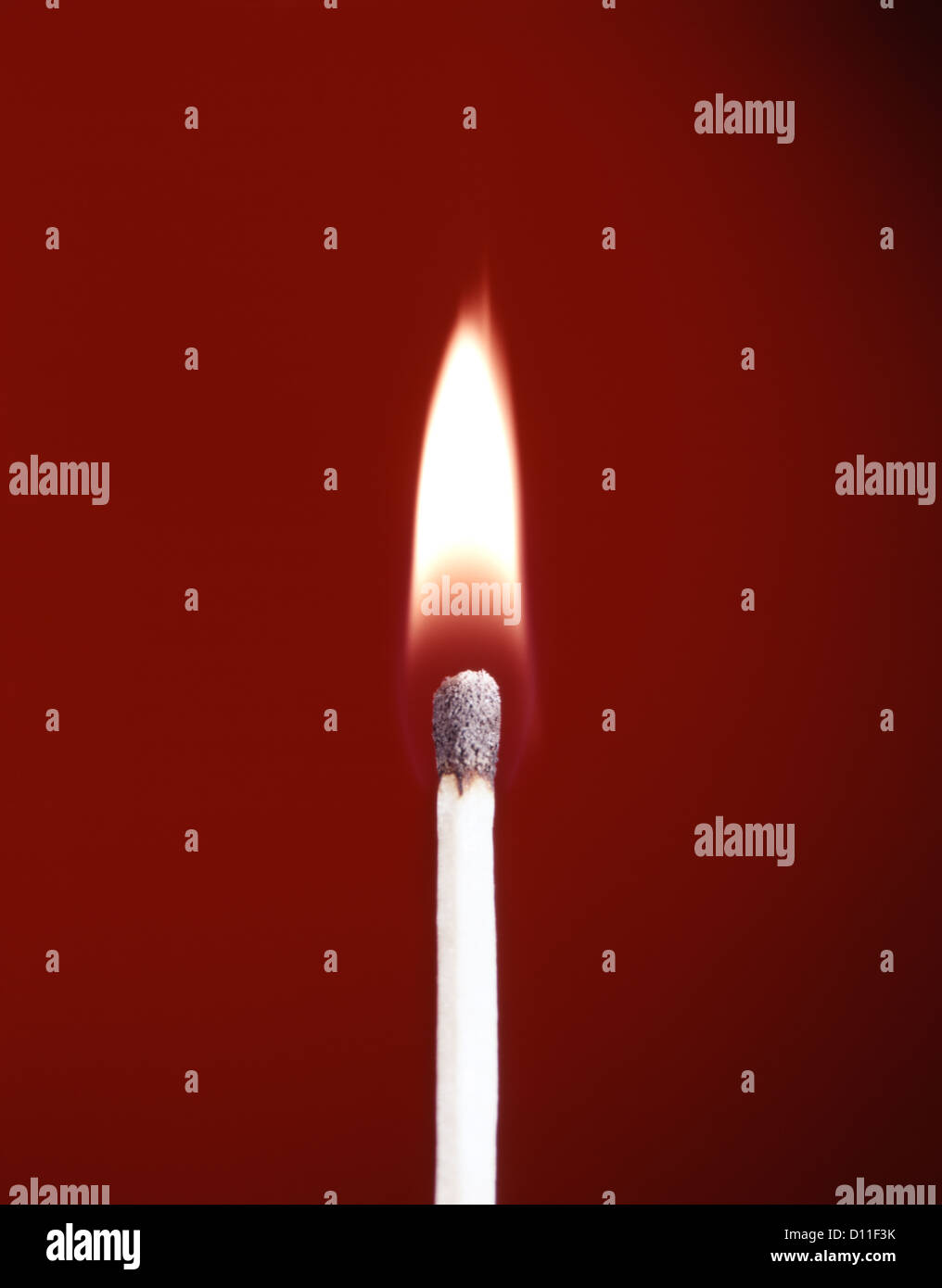 1970s BURNING WOODEN SAFETY MATCH ON RED BACKGROUND FLAME Stock Photo
