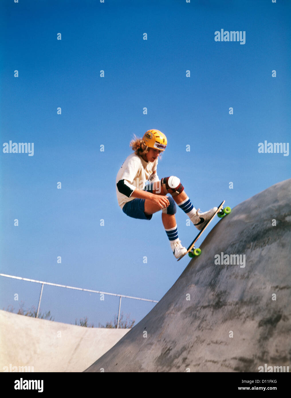 1970s TEENAGE BOY WEARING SAFETY EQUIPMENT SKATE BOARDING ON SKATEBOARD OBSTACLE COURSE Stock Photo