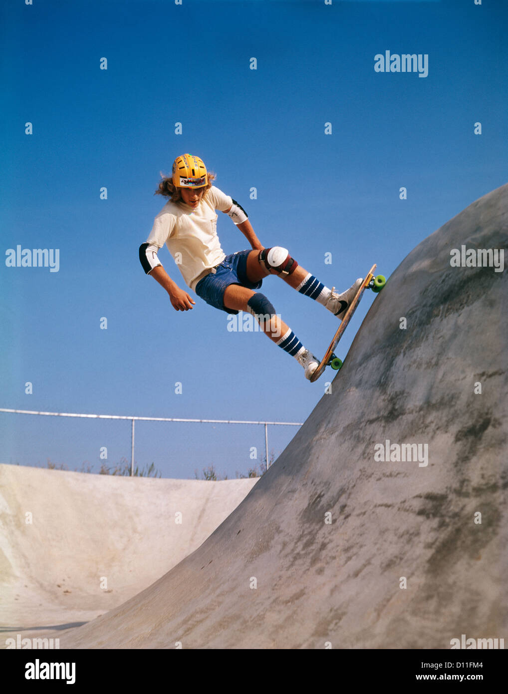 1970s TEENAGE BOY WEARING SAFETY EQUIPMENT SKATE BOARDING ON SKATEBOARD OBSTACLE COURSE Stock Photo