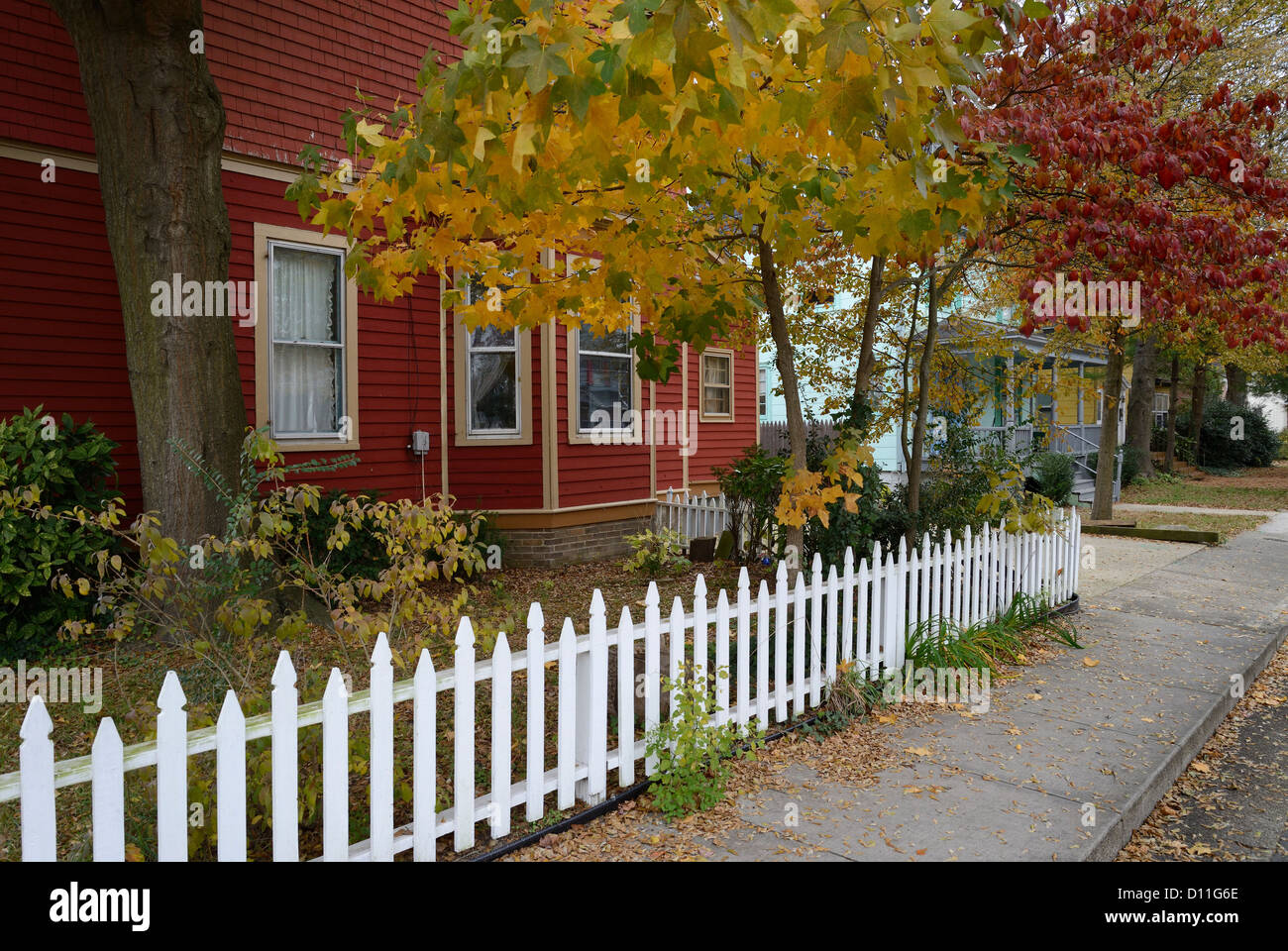 Red House & White Picket Fence In Quiet Neighborhood During Autumn Stock Photo