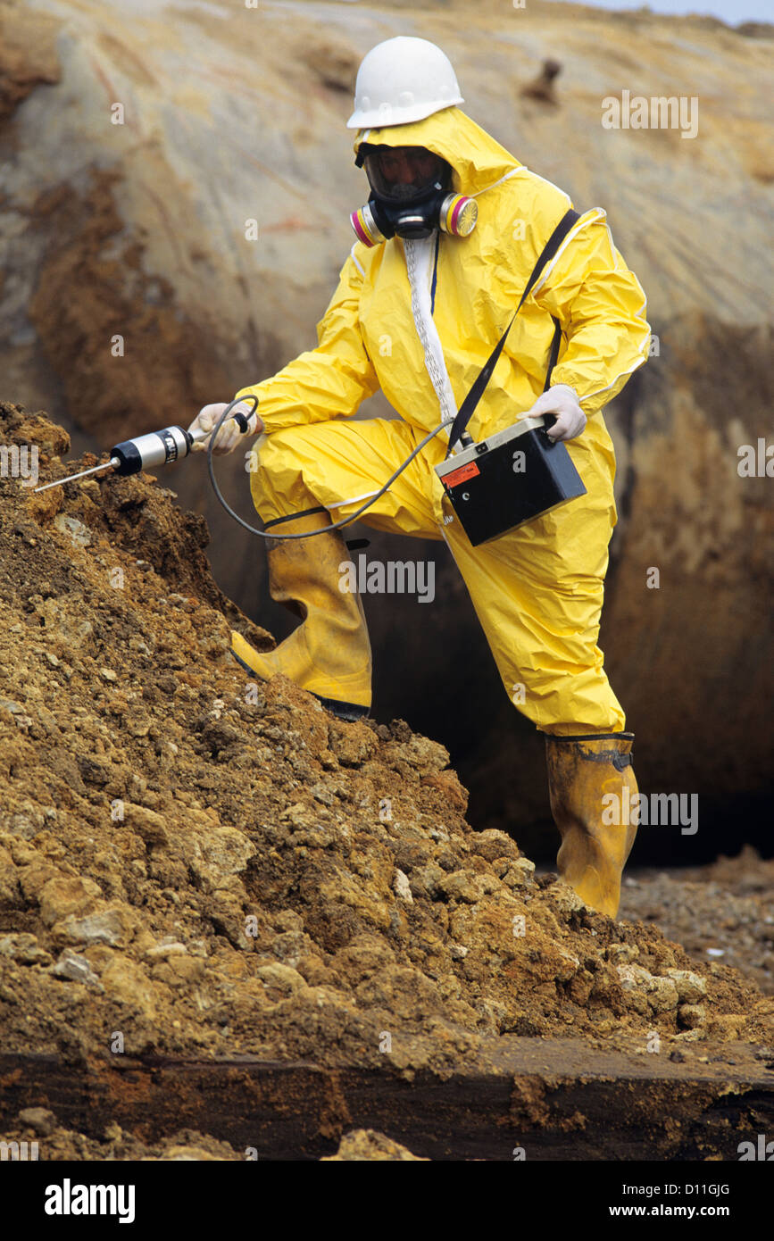 1990s WORKER IN SAFETY GEAR CHECKING SOIL FOR OIL CONTAMINATION Stock ...