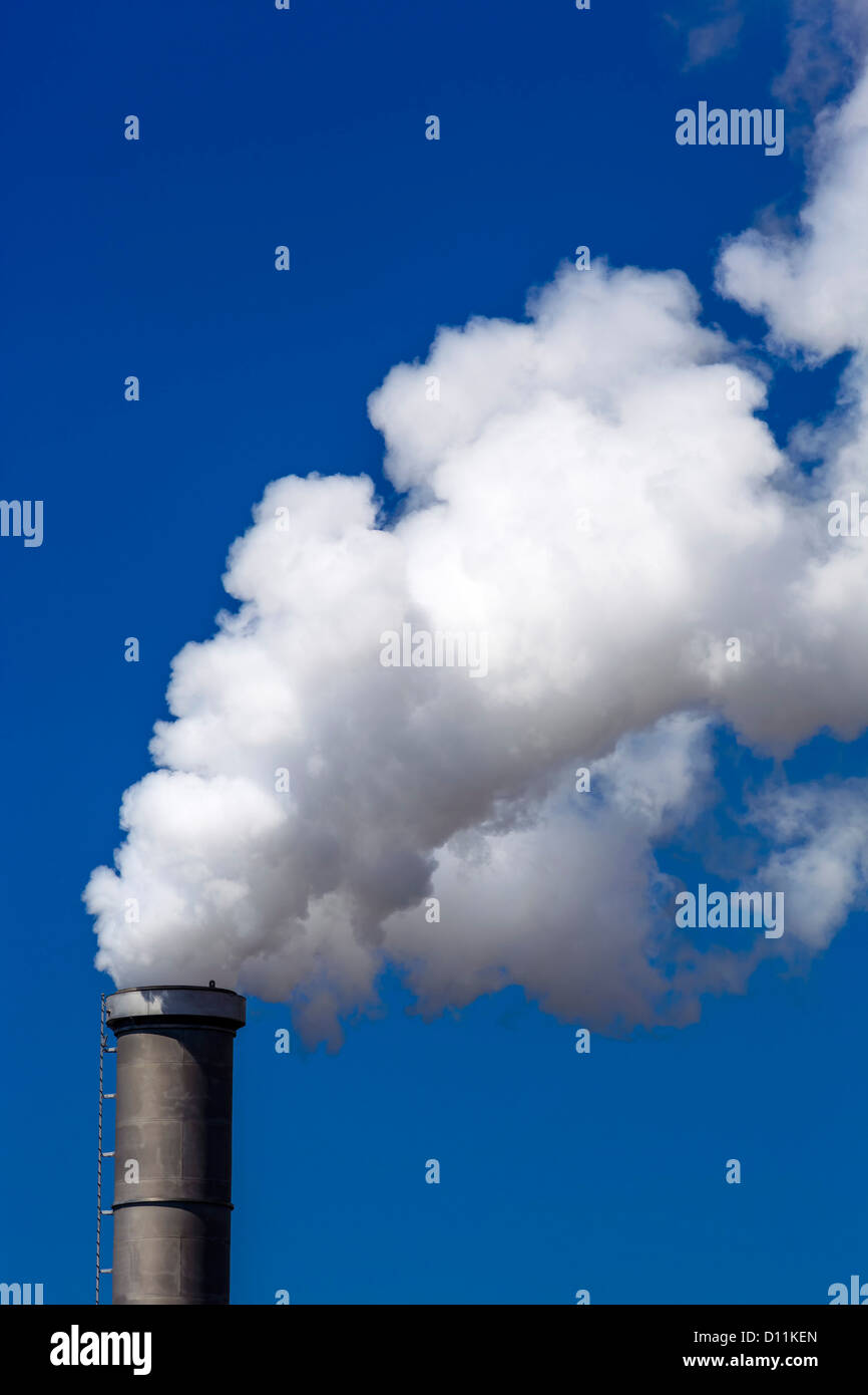 Germany, Chimney with white smoke against blue sky Stock Photo
