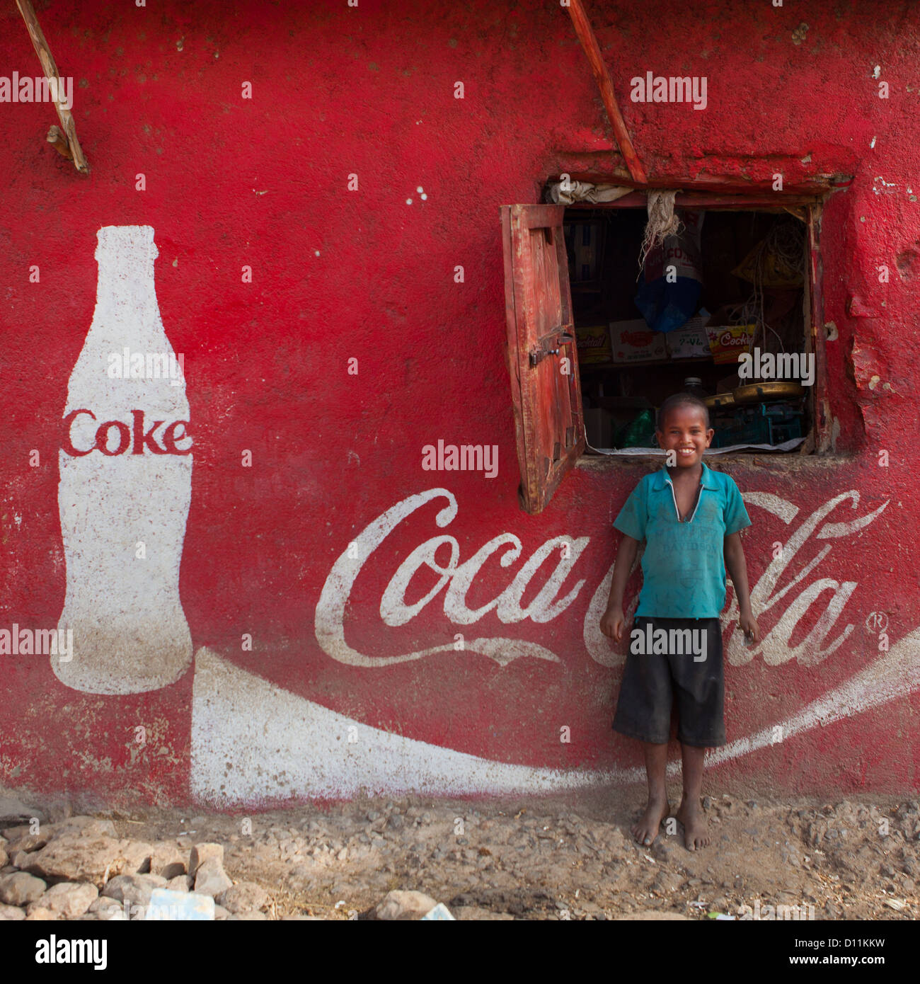 Smiling Kid Standing In Front Of A Wall Painted With A Coca Cola Advertisement, Dire Dawa, Ethiopia Stock Photo