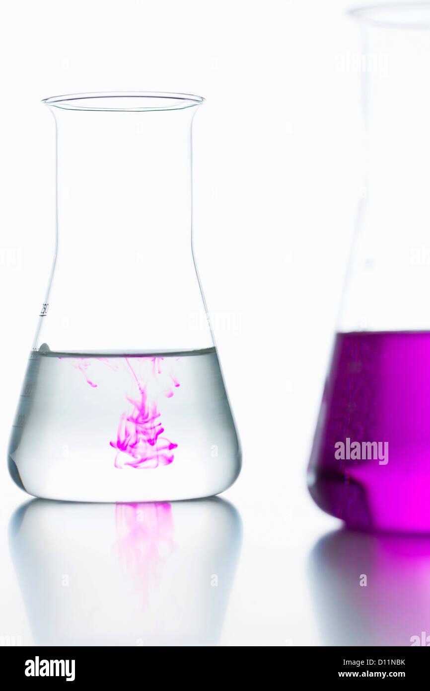 Volumetric flasks with colorless and pink on white background, close up Stock Photo