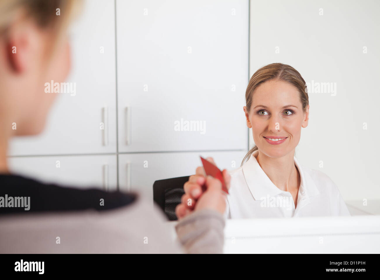 Germany, Patient giving insurance card to receptionist in dental office