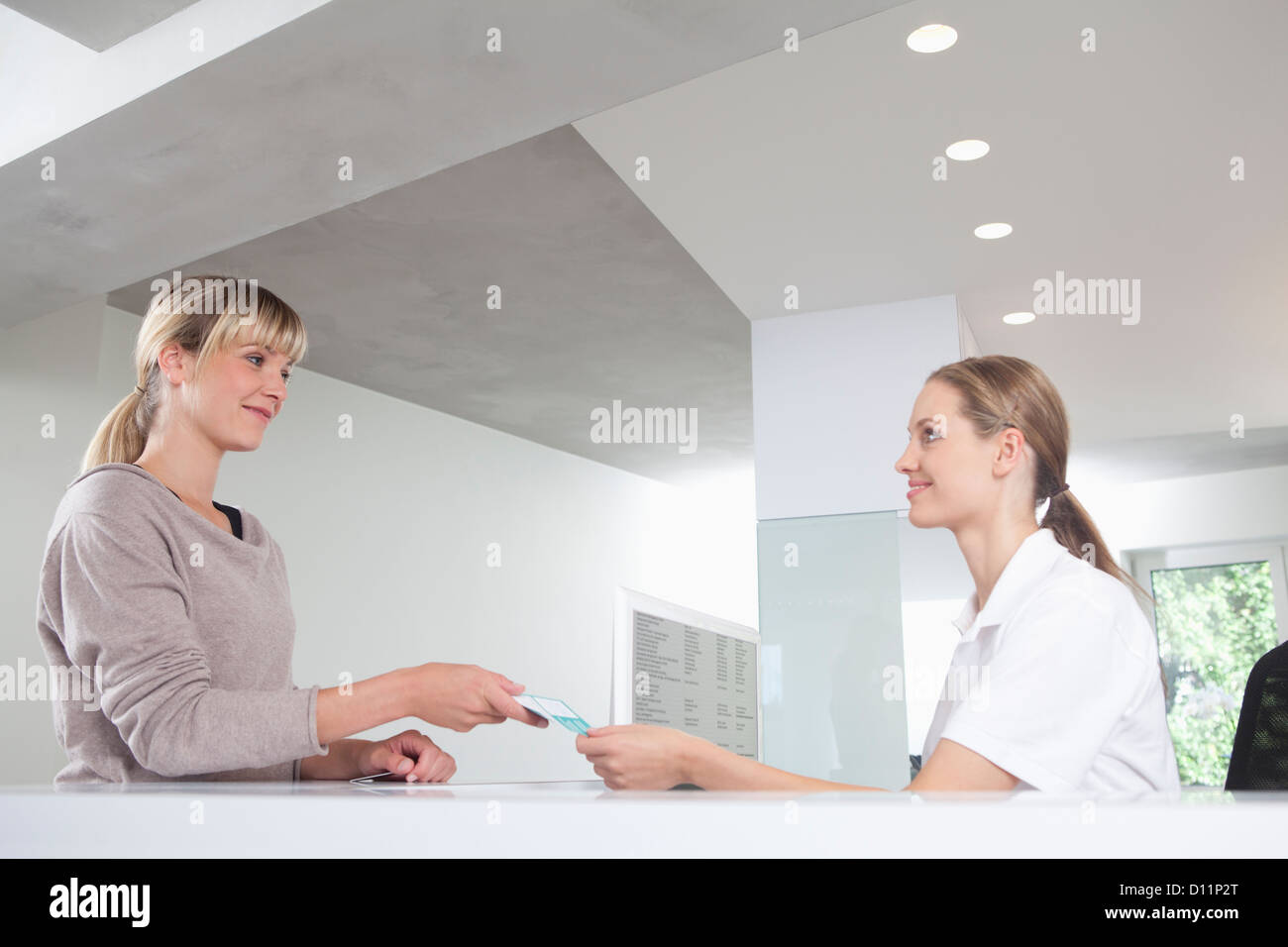 Germany, Patient giving insurance card to receptionist in dental office