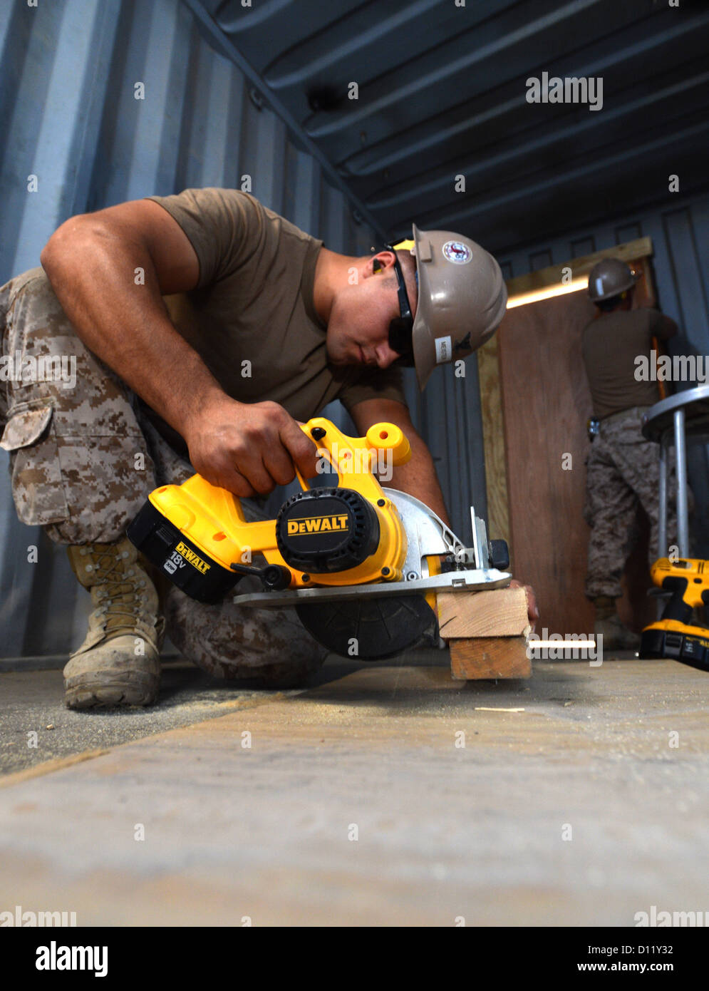 Builder 3rd Class Joel Meister, assigned to Naval Mobile Construction Battalion (NMCB) 133, cuts wood to make various wedges when installing a door frame during a U.S. Coast Guard training facility repair project. NMCB 133 is deployed with Commander, Task Stock Photo