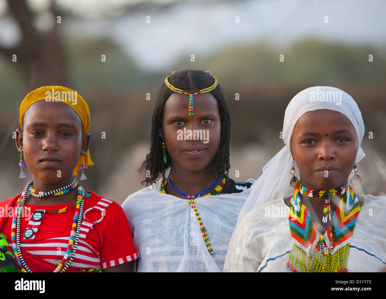 Three Smiling Karrayyu Tribe Girls With Stranded Hair, Colourful Jewels And Headscarfs At Gadaaa Ceremony, Metehara, Ethiopia Stock Photo