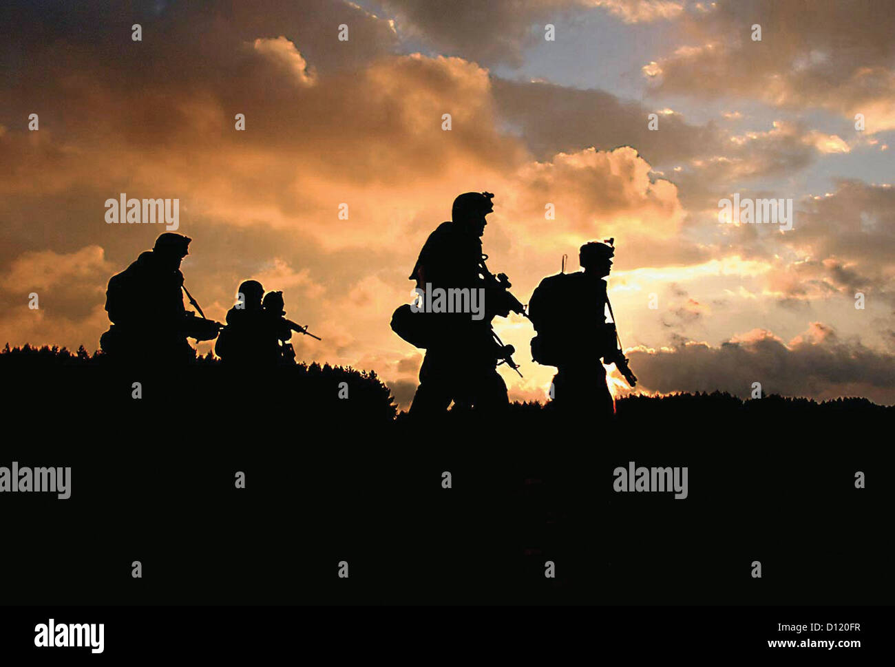 A US Army scout team moves at sunset to a landing zone to await pickup by a Black Hawk helicopter during a combat search and rescue training mission September 27, 2010 in Drawsko Pomorskie, Poland. Stock Photo