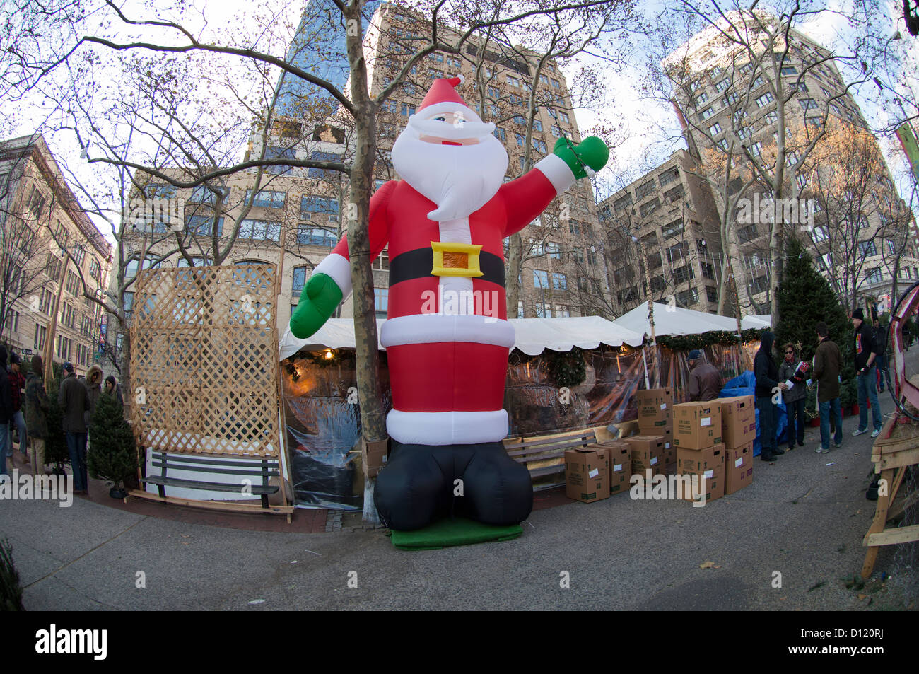 A giant inflated Santa Claus presides over a stand selling Christmas trees in the Soho neighborhood of New York Stock Photo
