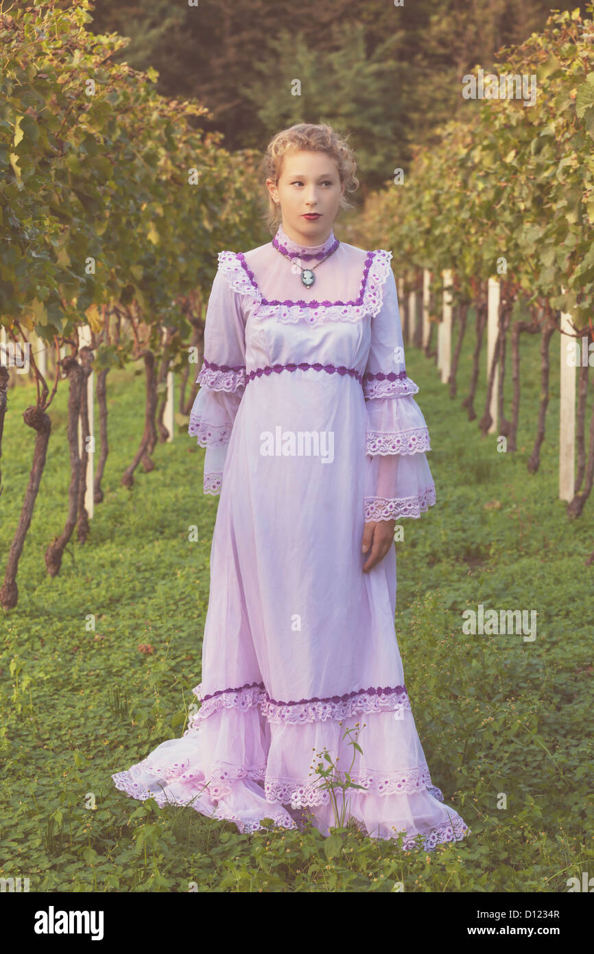a girl in a pink wedding dress is standing in a vineyard Stock Photo