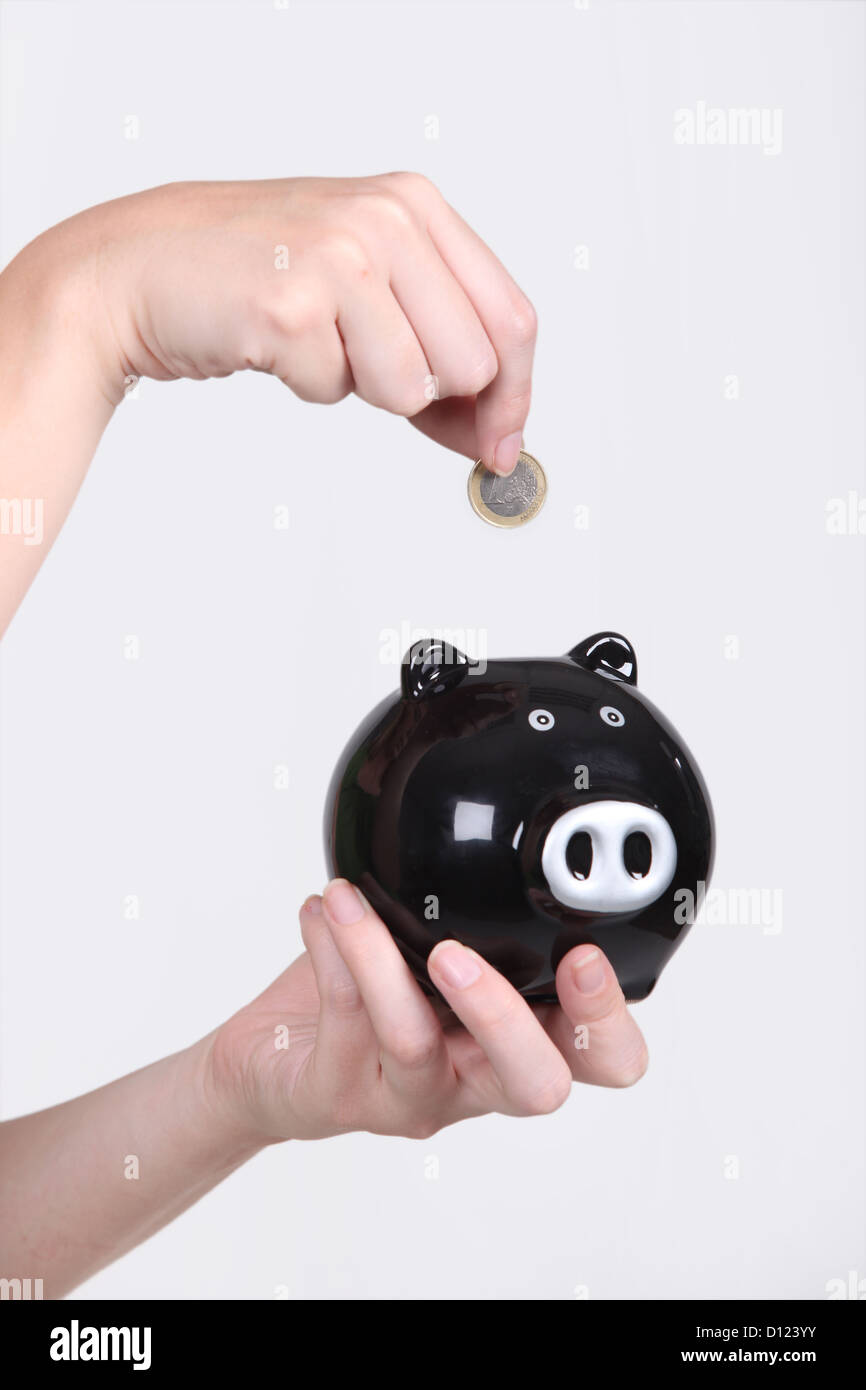 Close up of child's hand putting a euro into a piggy bank Stock Photo ...