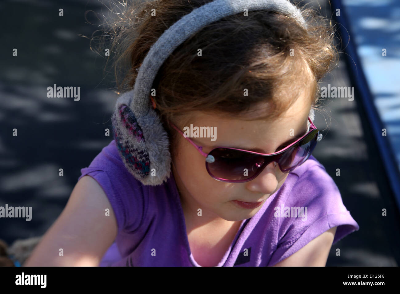 Girl Wearing Ear Muffs And Sunglasses In Garden Surrey England Stock