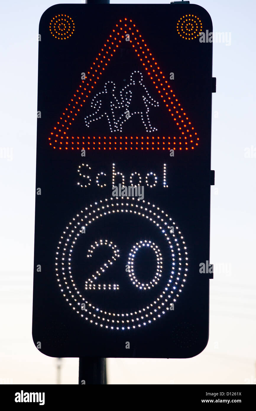 20 mile per hour 20 mph warning school flashing sign UK red showing mother and child safety road speed limit slow down be seen o Stock Photo