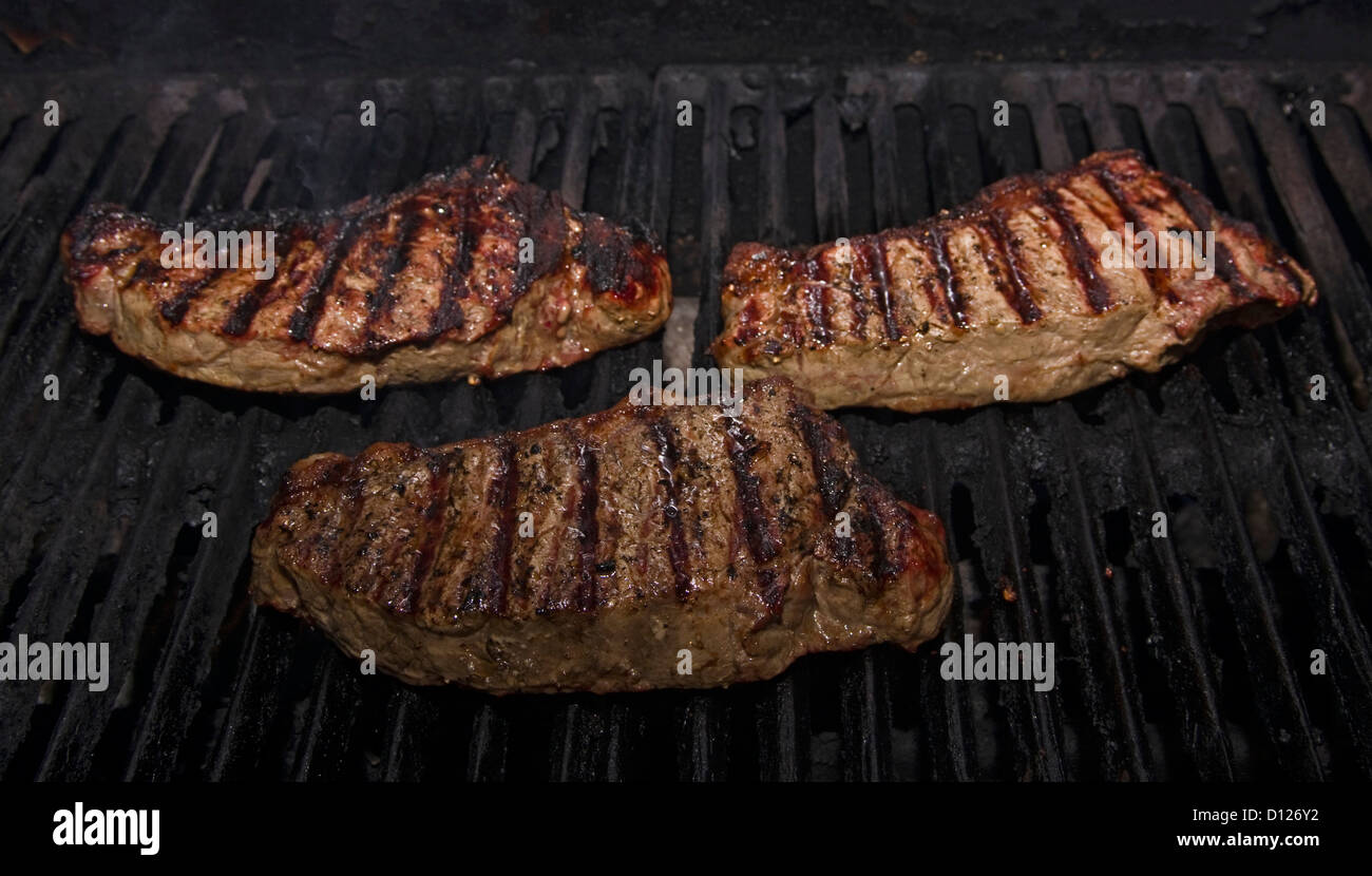 New York steaks on bbq Stock Photo Alamy