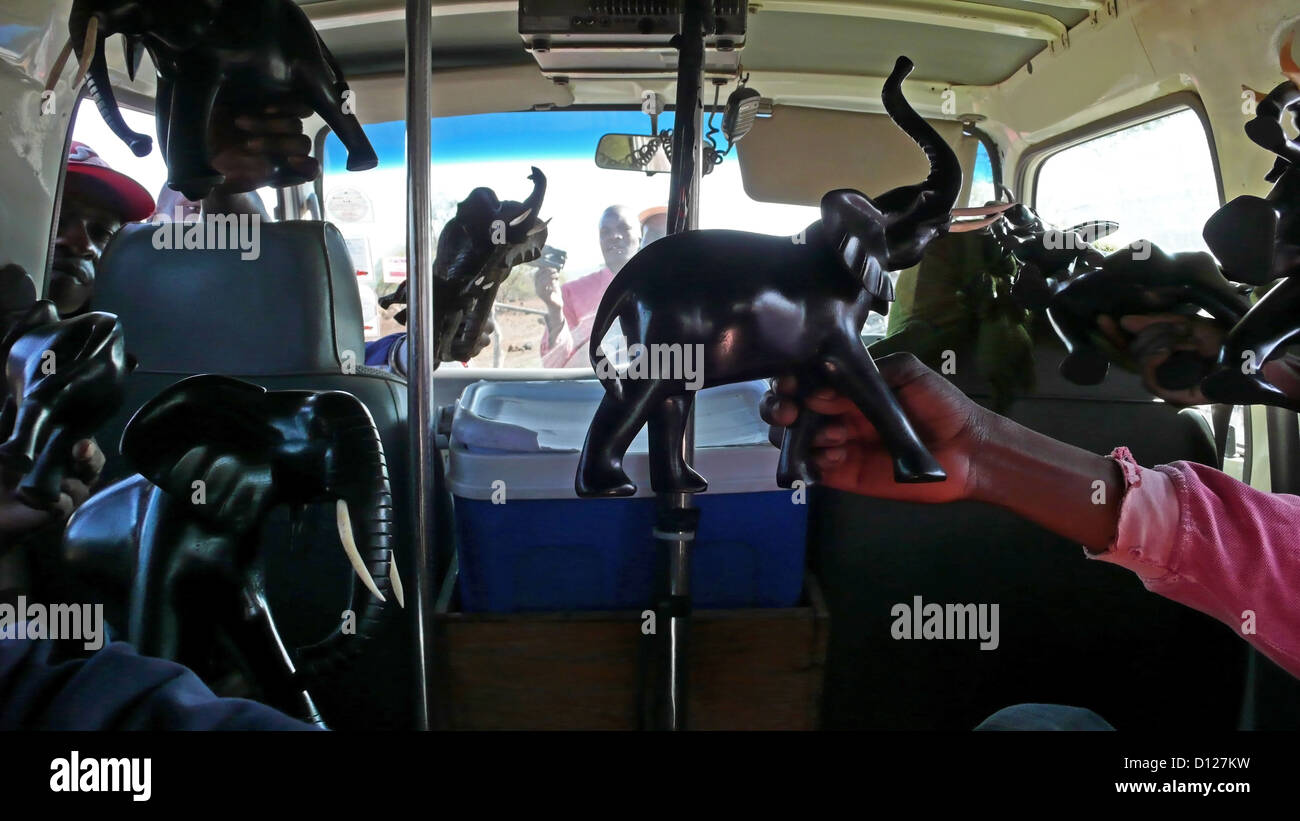 Locals trying to sell wooden carvings to tourists in a mini bus, Tsavo East National Park, Kenya, East Africa. 6/2/2009. Photograph: Stuart Boulton Stock Photo