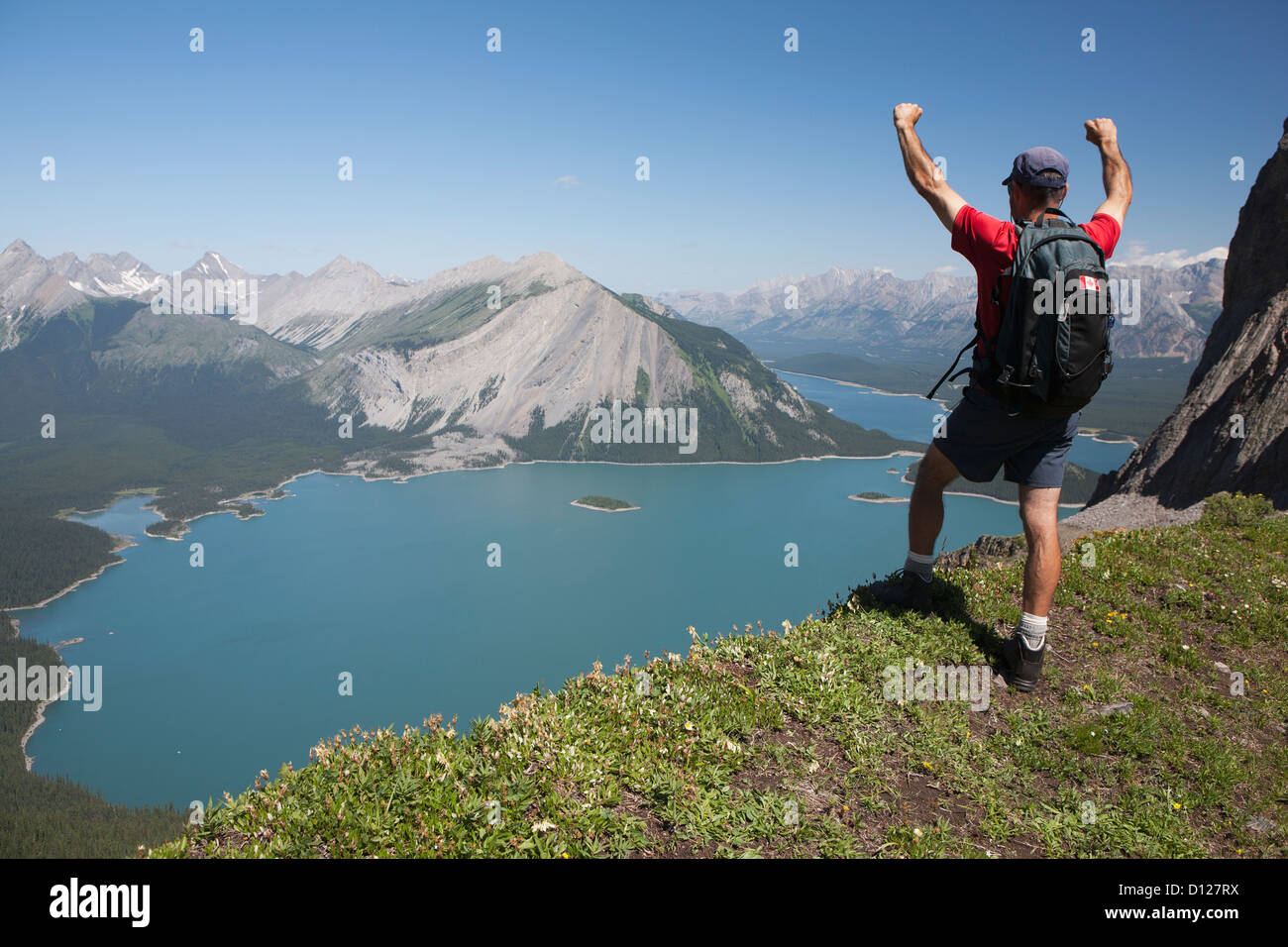 A hiker standing with arms up on a mountain ridge overlooking an ...