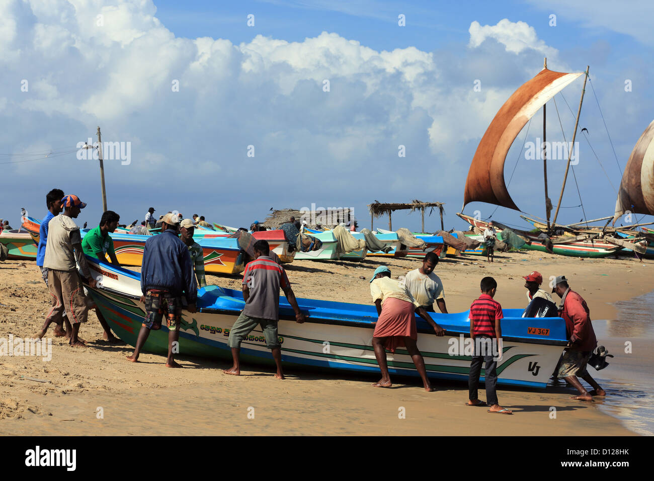 Fishermen use teamwork to haul a heavy fishing boat up the beach Stock ...