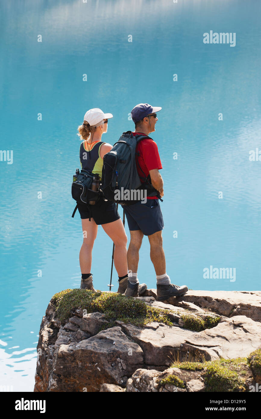 Female And Male Hikers On Rock Cliff Overlooking Mountain Lake; Field ...