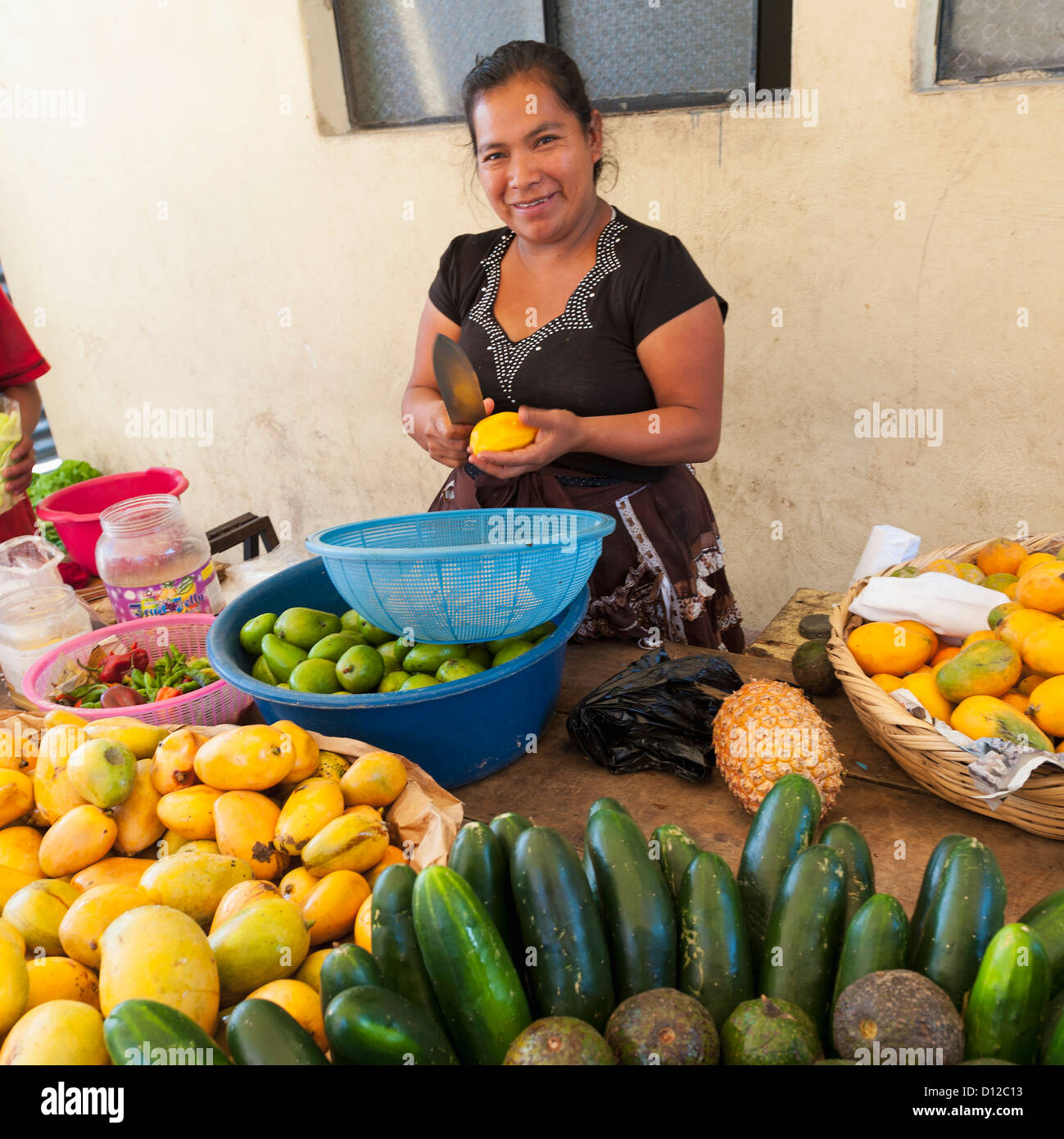 A Woman Cuts Fruit Into A Bowl With Large Quantities Of Produce On The ...