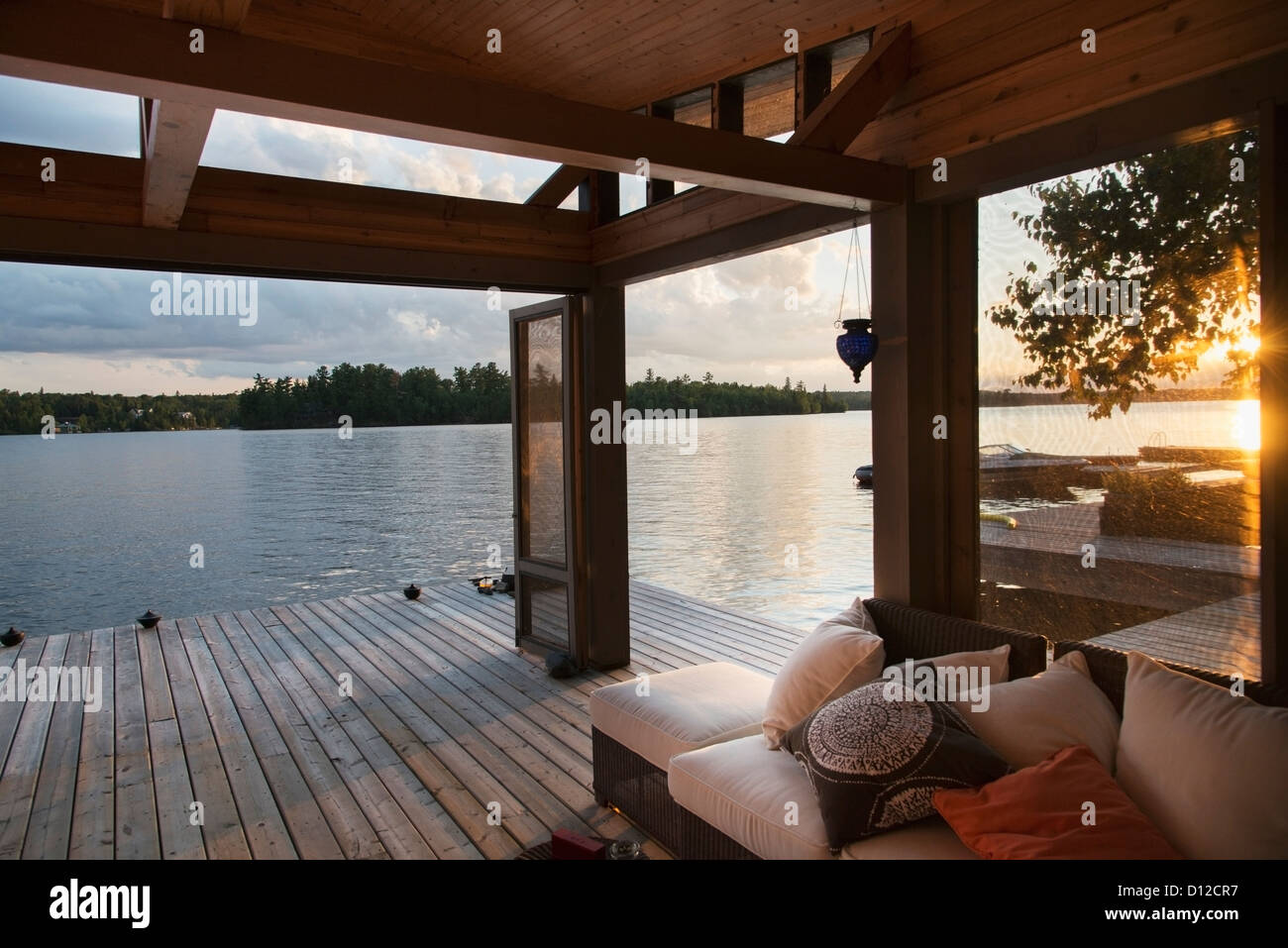 Covered Patio On A Wooden Deck On The Water's Edge At Sunset; Lake Of