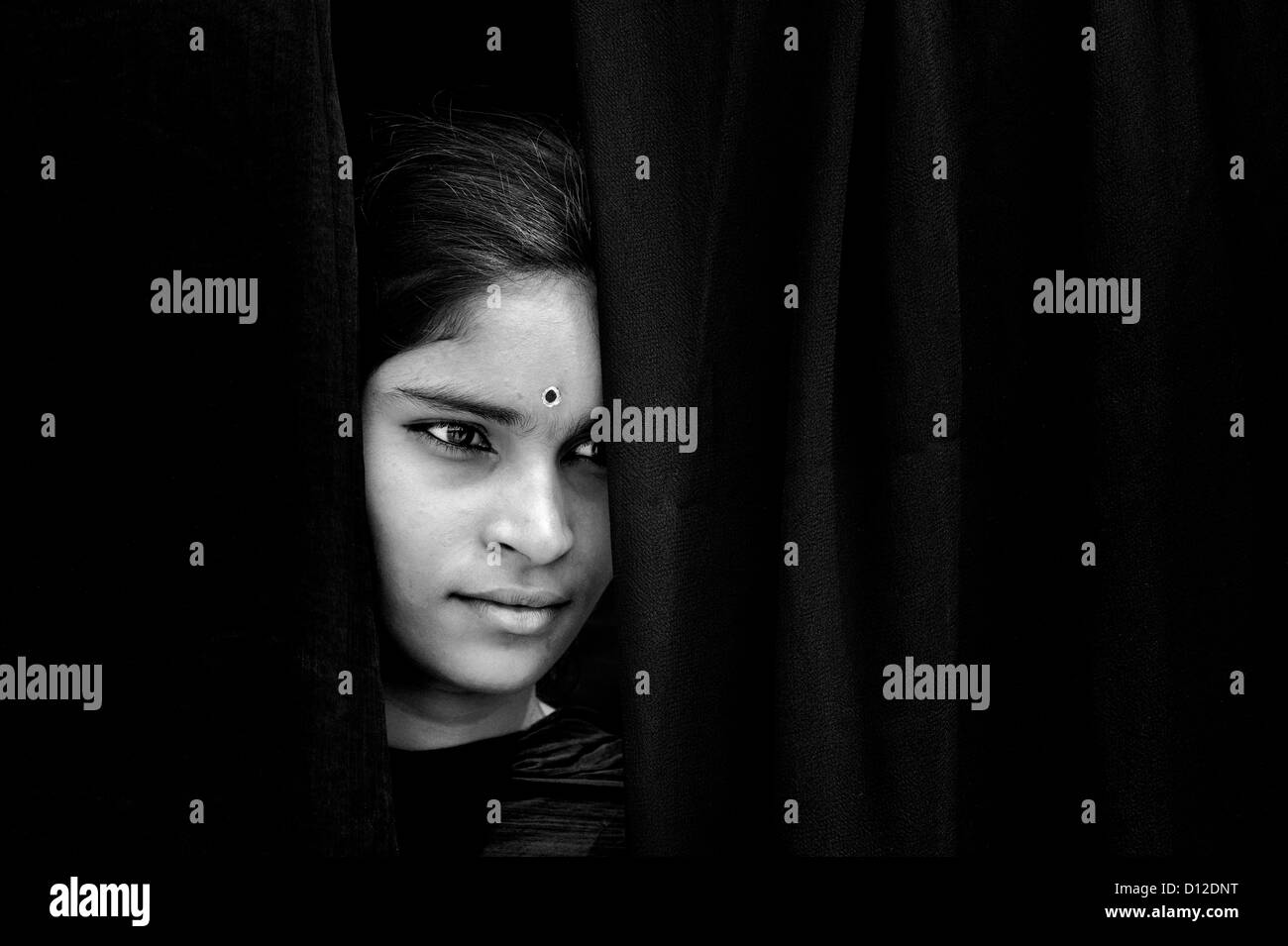 Indian girl face looking through dark shawls. India. Black and white Stock Photo