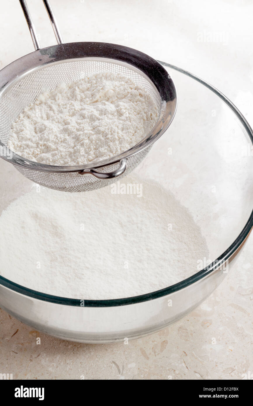 flour being sieved into bowl Stock Photo
