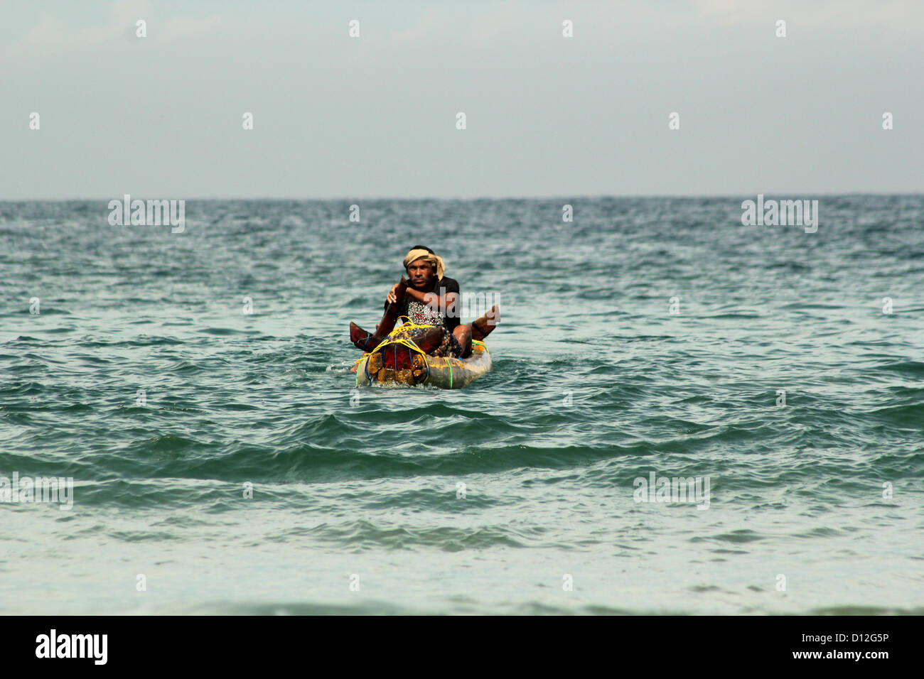 Fisherman rowing his traditional wood catamaran, Kovalam, Kerala, India Stock Photo