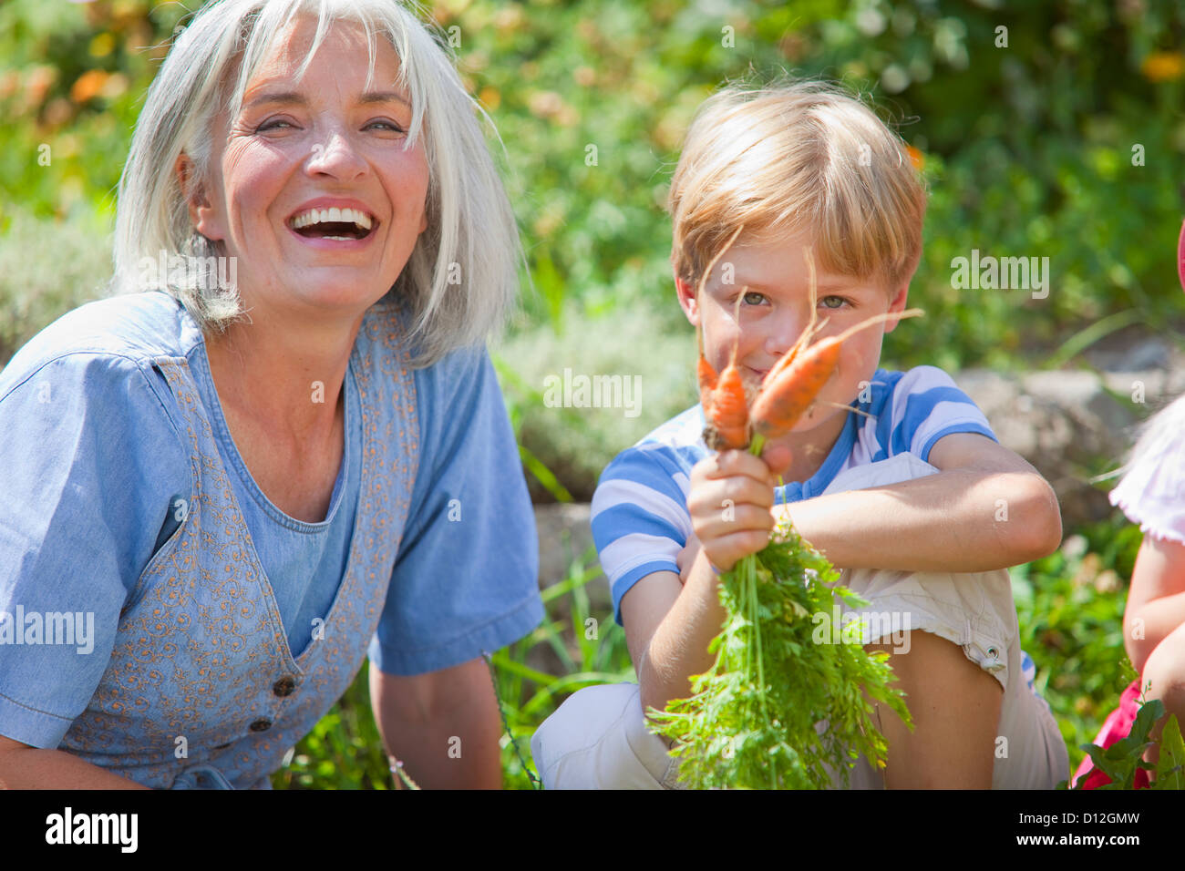 Germany, Bavaria, Mature woman and boy inspecting carrots in garden