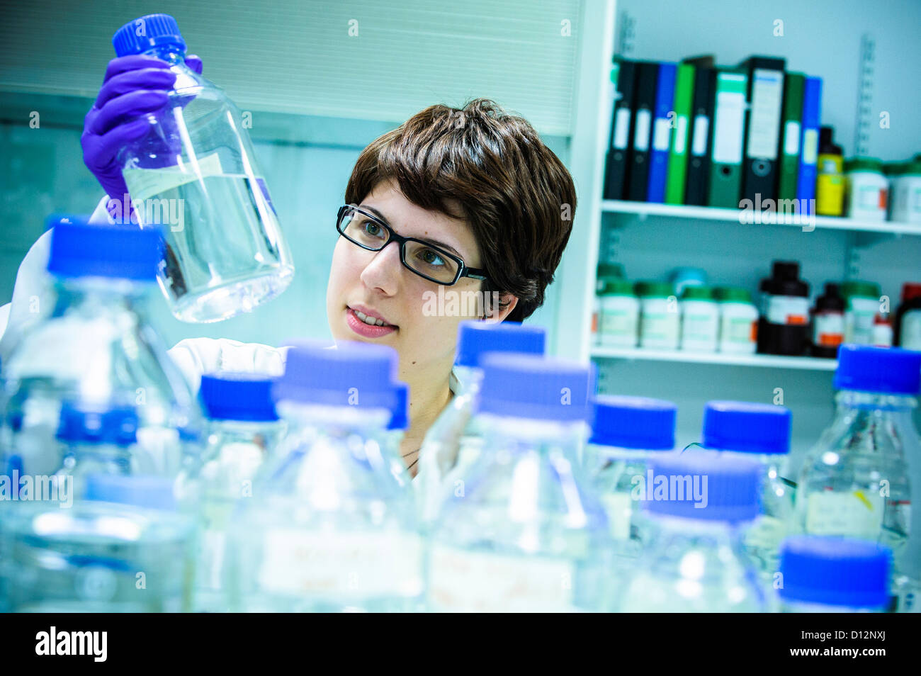 Young female scientist  in science lab holding a glass samples jar Stock Photo