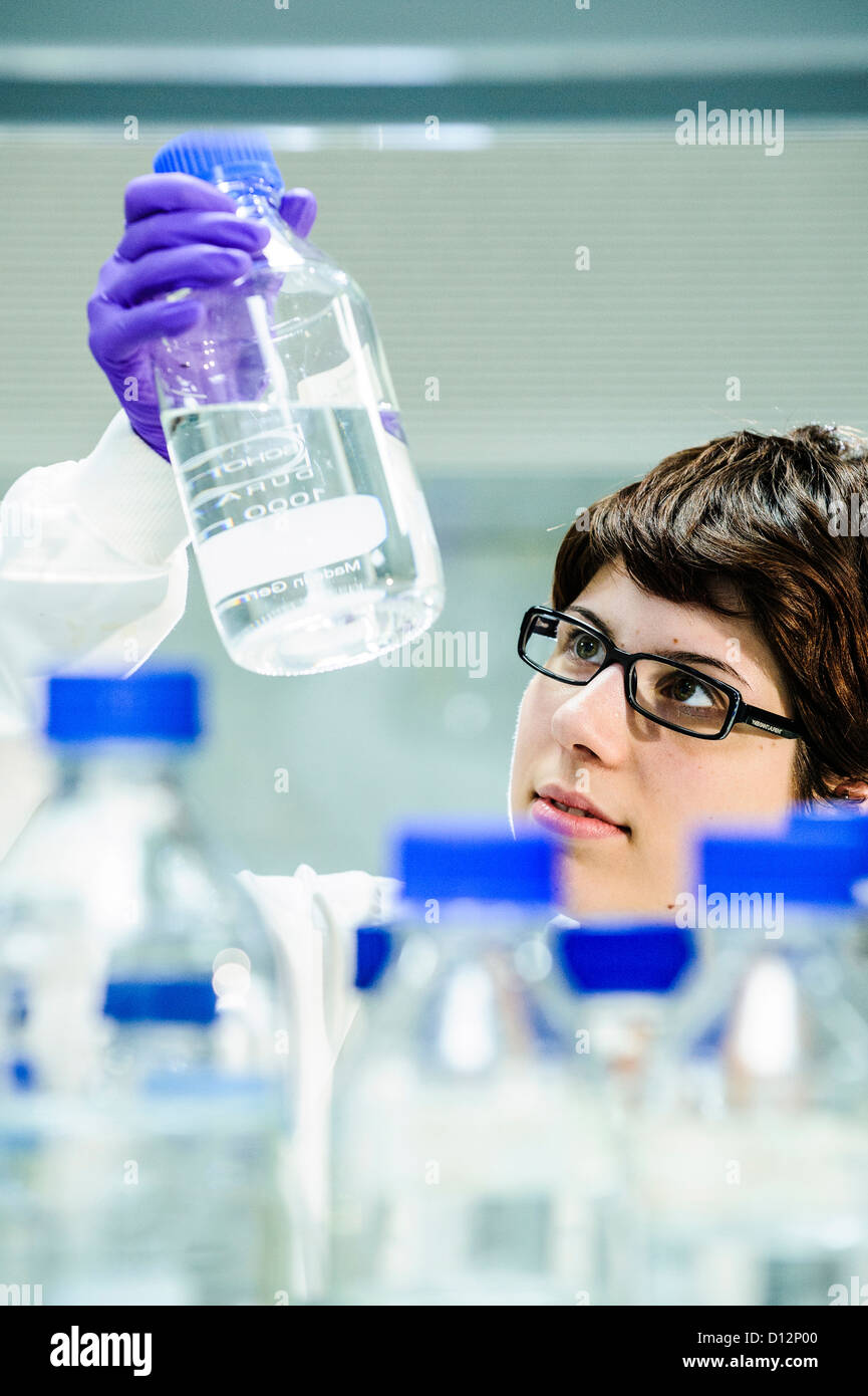 Young female scientist  in science lab holding a glass samples jar Stock Photo