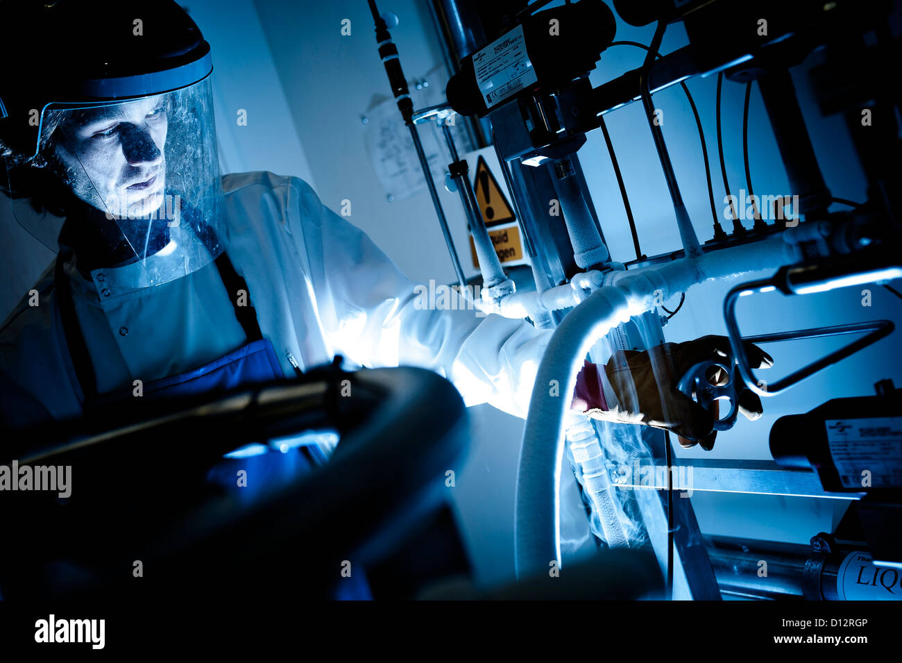 scientist wearing  visor and protective gloves opens liquid nitrogen valve Stock Photo
