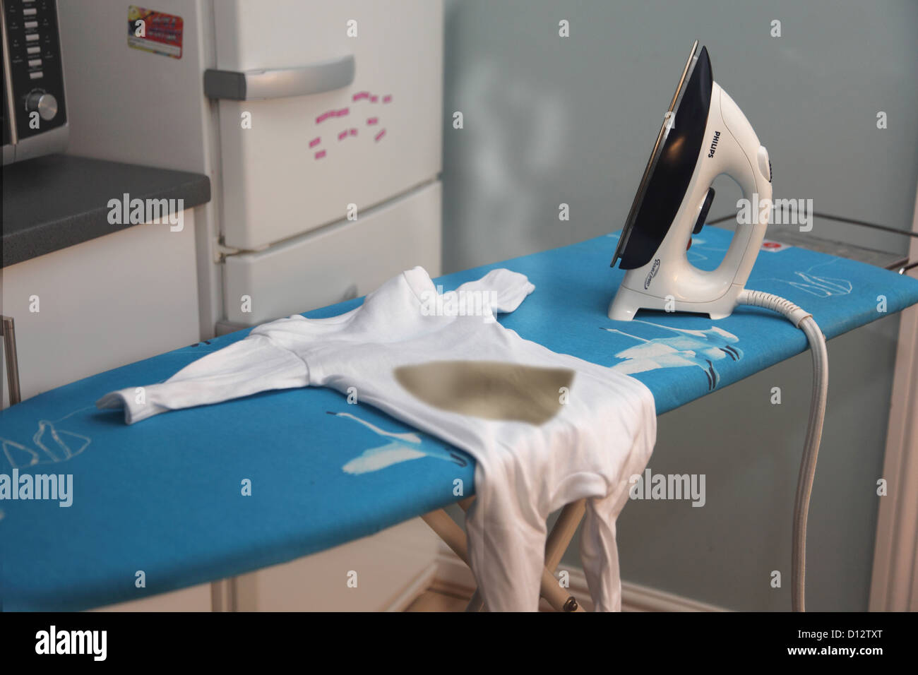 Ironing board showing a baby's clothing burnt by the iron Stock Photo