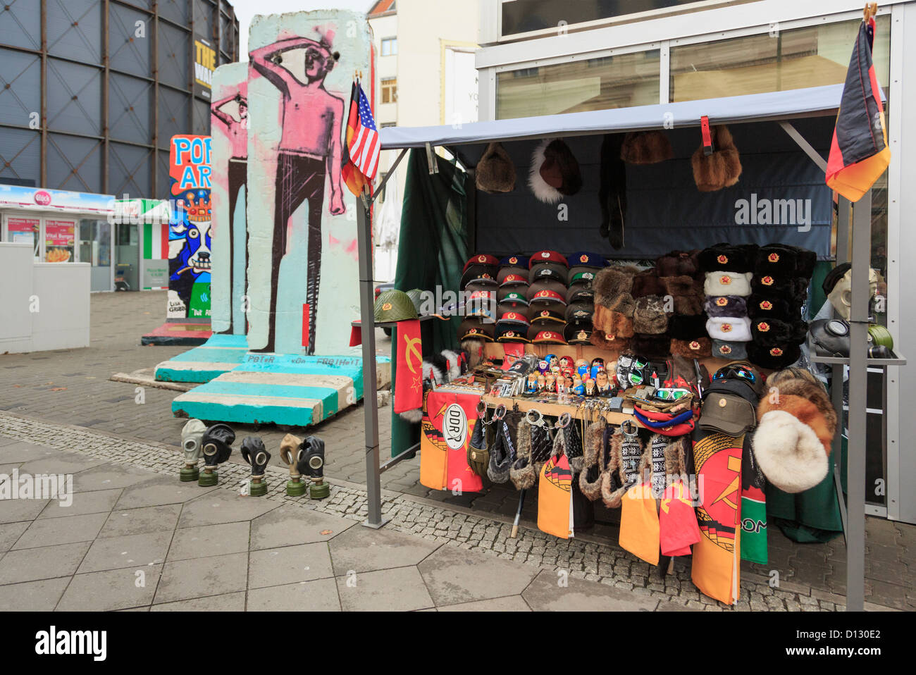 Stall selling DDR army and war memorabilia as souvenirs near sections of the original wall on Friedrichstrasse, Berlin, Germany Stock Photo