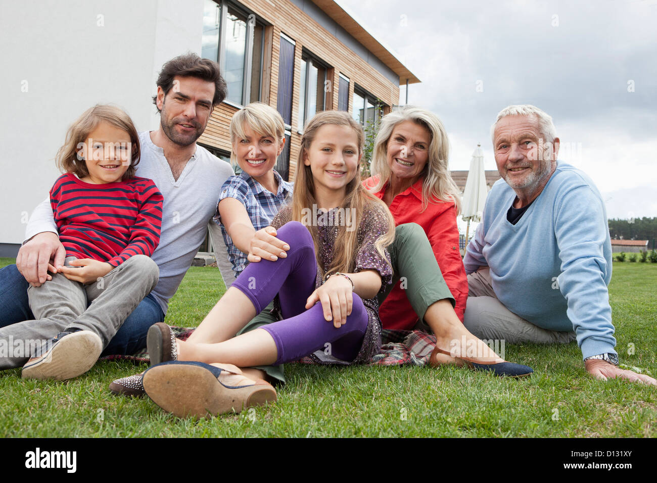 Germany, Bavaria, Nuremberg, Family sitting in front of house, smiling, portrait Stock Photo
