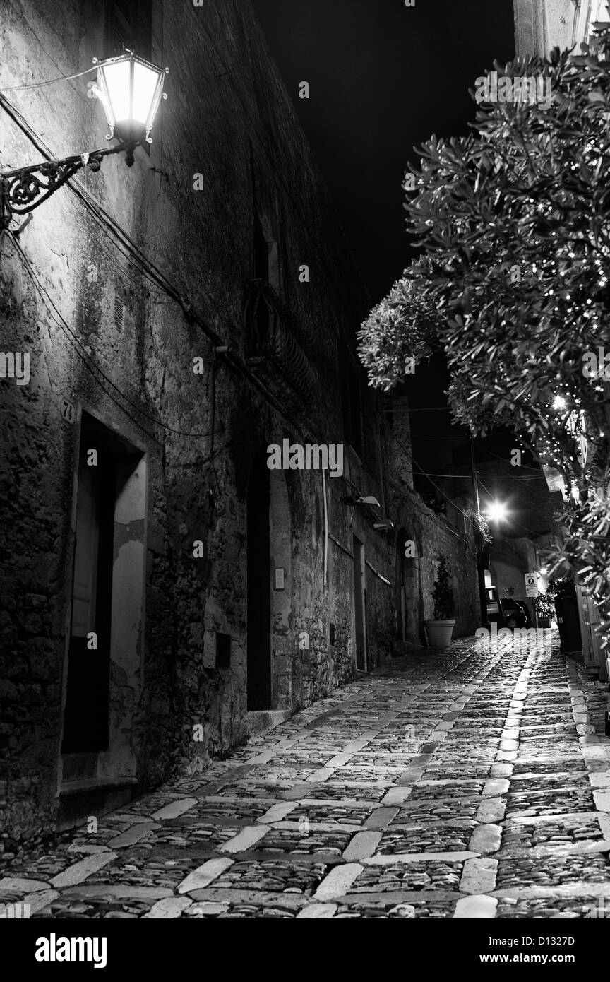Narrow cobblestone street illuminated by light at night Stock Photo - Alamy