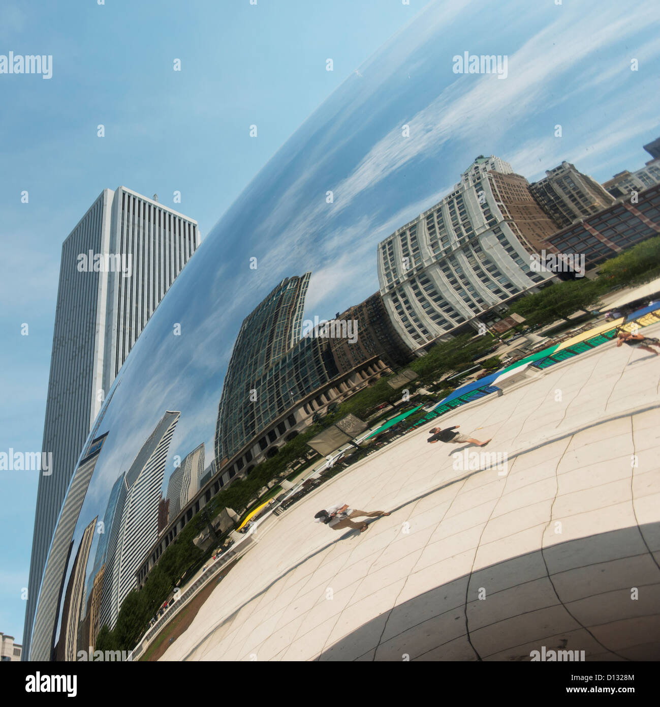 buildings and pedestrians reflected in a silver rounded sculpture