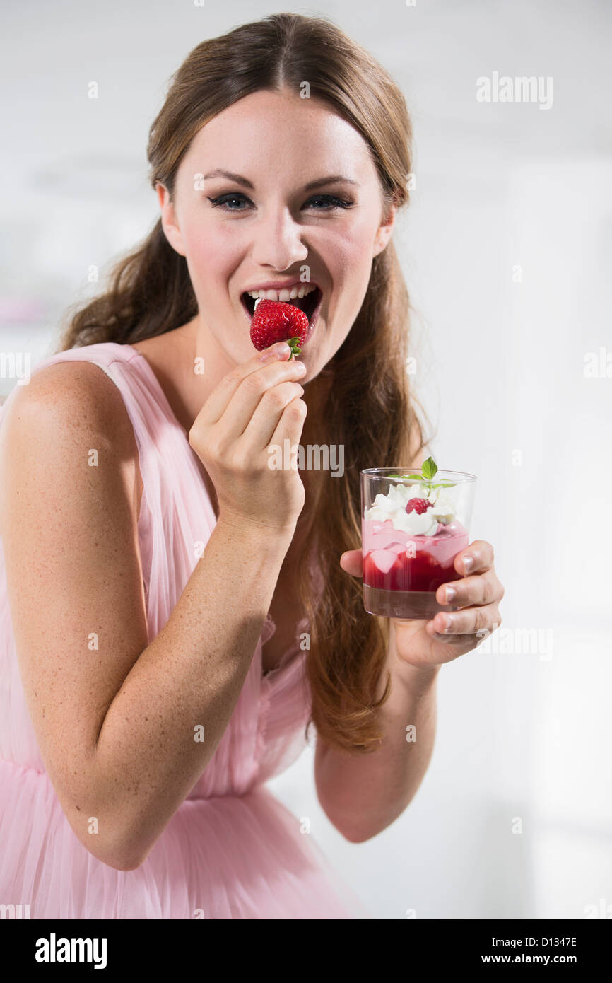 Germany, Young woman biting strawberry, close up Stock Photo - Alamy