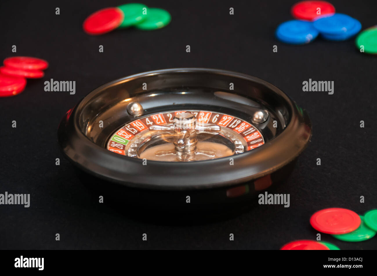 Miniature roulette wheel and cash chips. Stock Photo