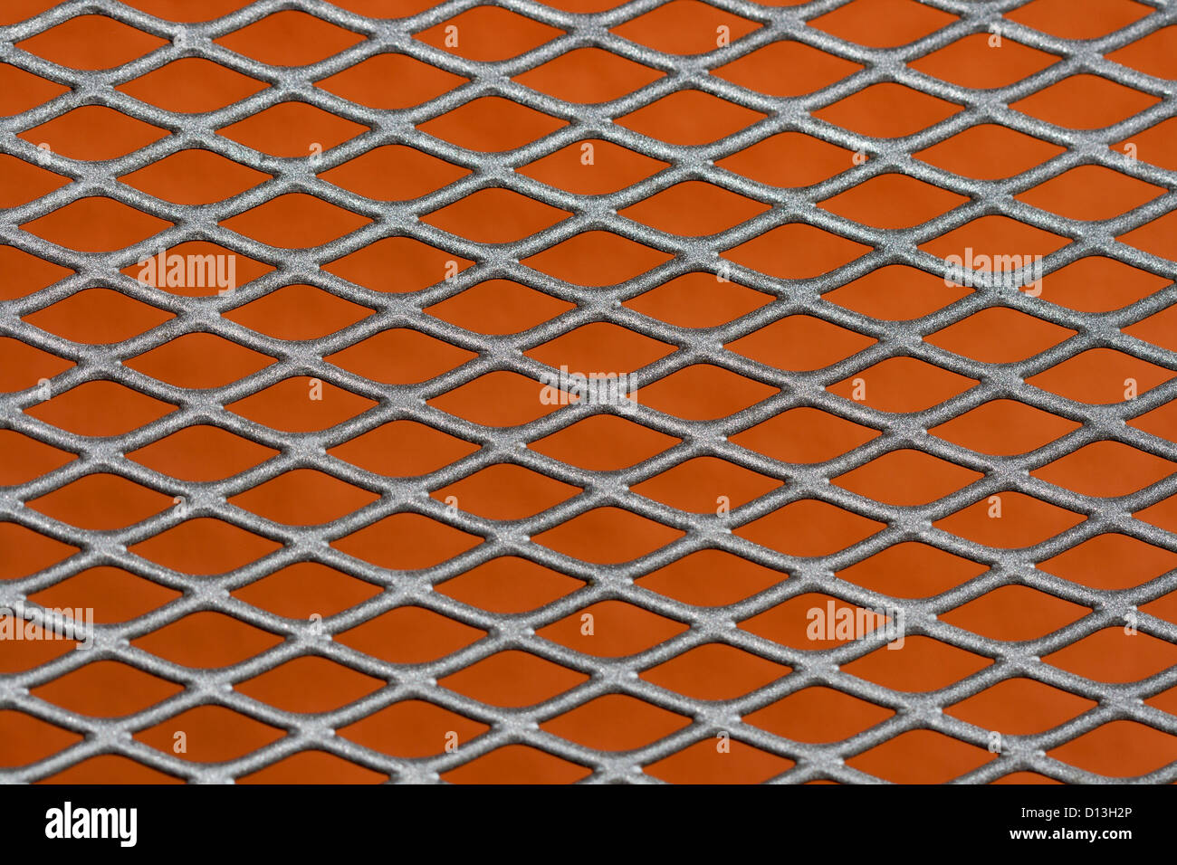 Abstract metal grating against red wall background Stock Photo