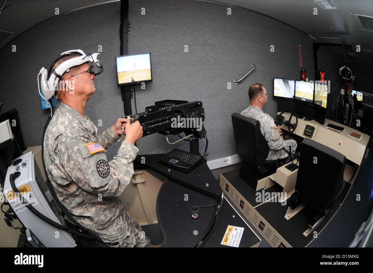 A US Army Soldier operates the VRCT .50 cal. virtual machine gun while another soldier is at the controls of the Virtual Route Clearance Trainer Husky vehicle mounted mine detector September 10, 2009 in Wisconsin. Stock Photo