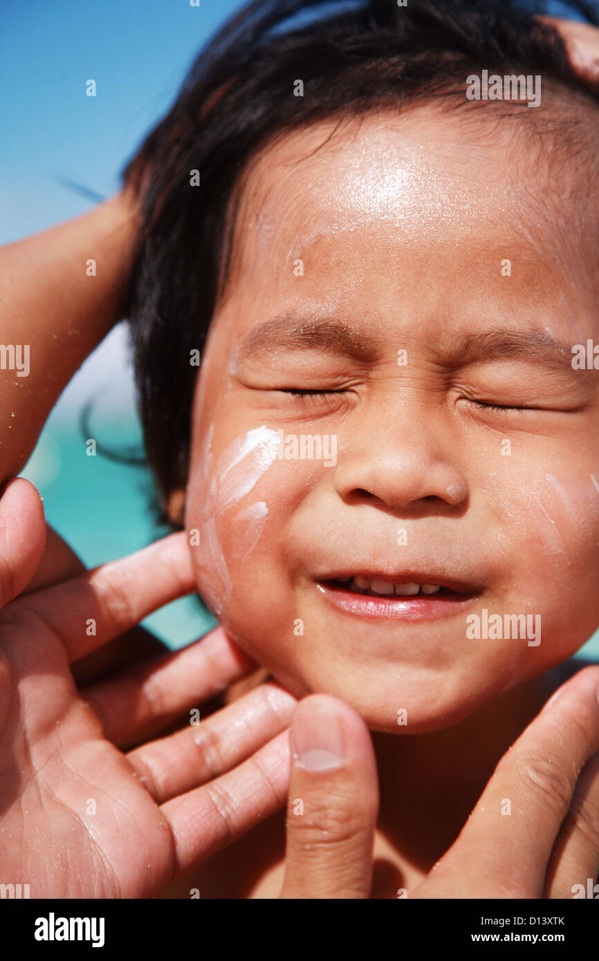 Hawaii, Oahu, Parent Putting Sunscreen Lotion On Child's Face At The