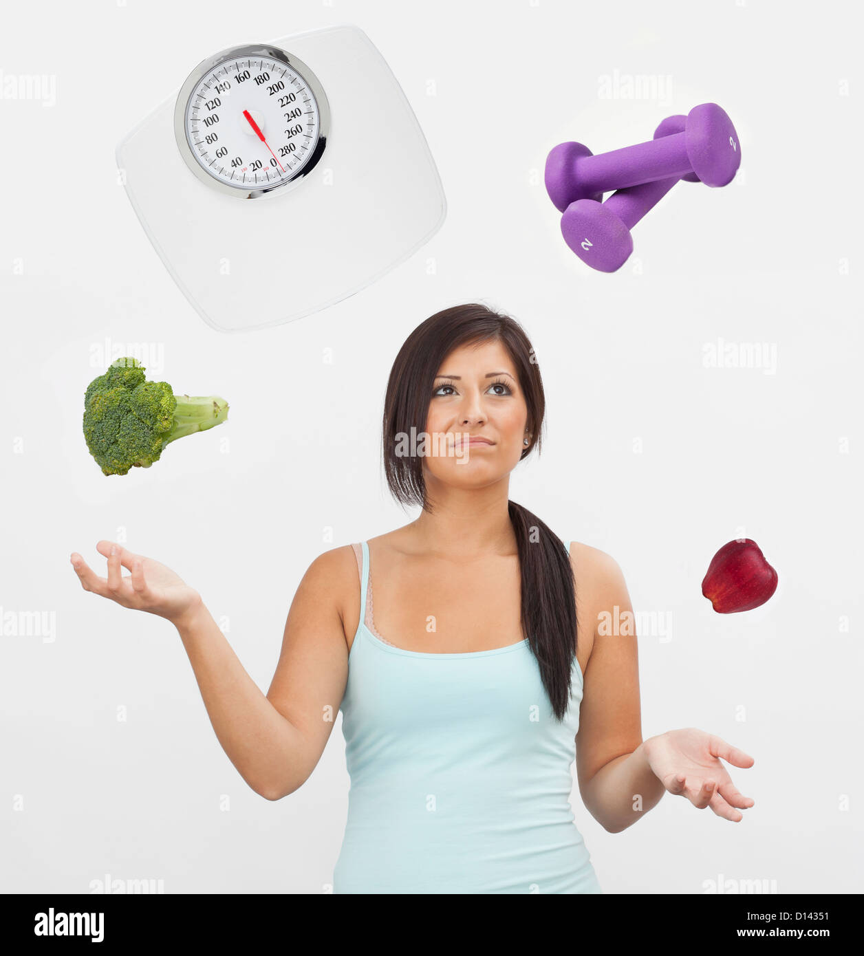 Studio shot of young woman juggling with weight scale, weights, fruit and vegetable Stock Photo