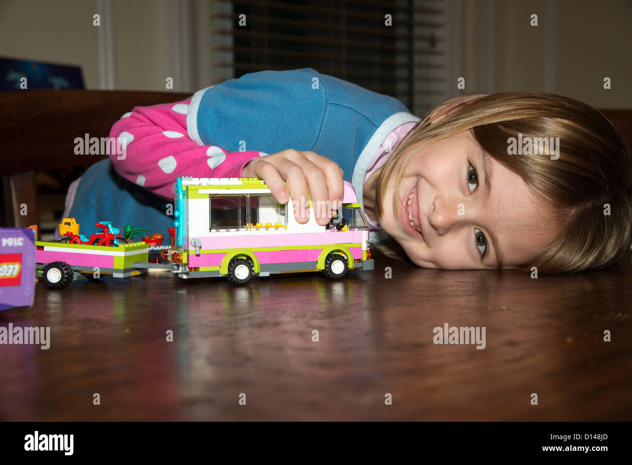 Child playing on a table with a lego campervan she has built Stock Photo