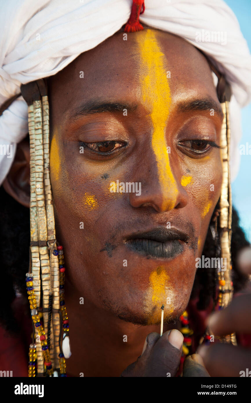 Man from Wodaabe nomadic tribe painting face - Stock Image - C055/0222 -  Science Photo Library