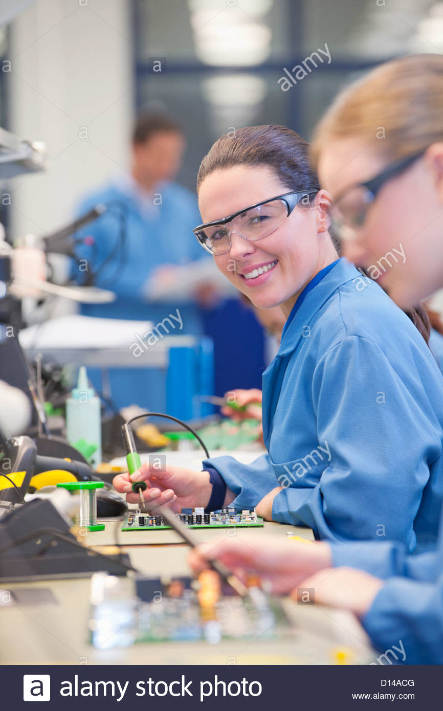 portrait of smiling technician soldering circuit board on productionportrait of smiling technician soldering circuit board on production line in manufacturing plant