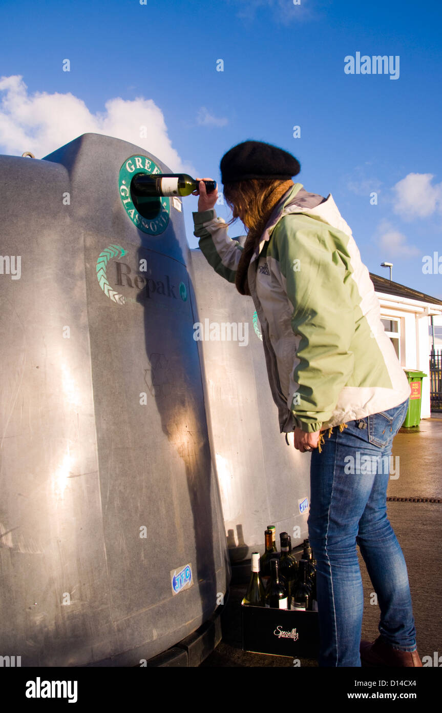Woman puts wine bottle into recycling bin Stock Photo