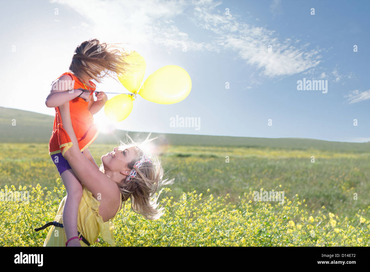 Sisters playing in field of flowers Stock Photo