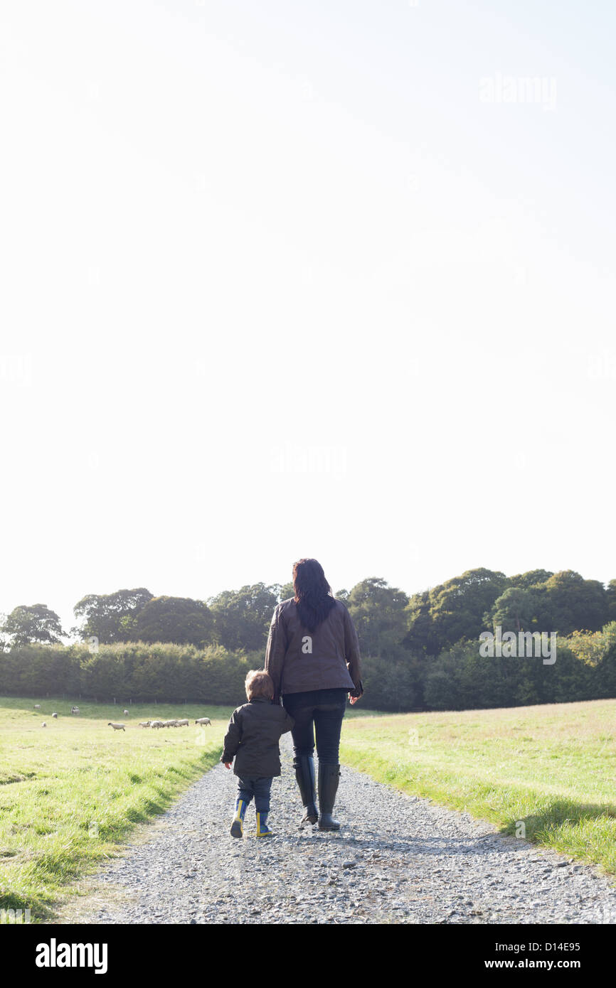 Mother and son walking on dirt road Stock Photo