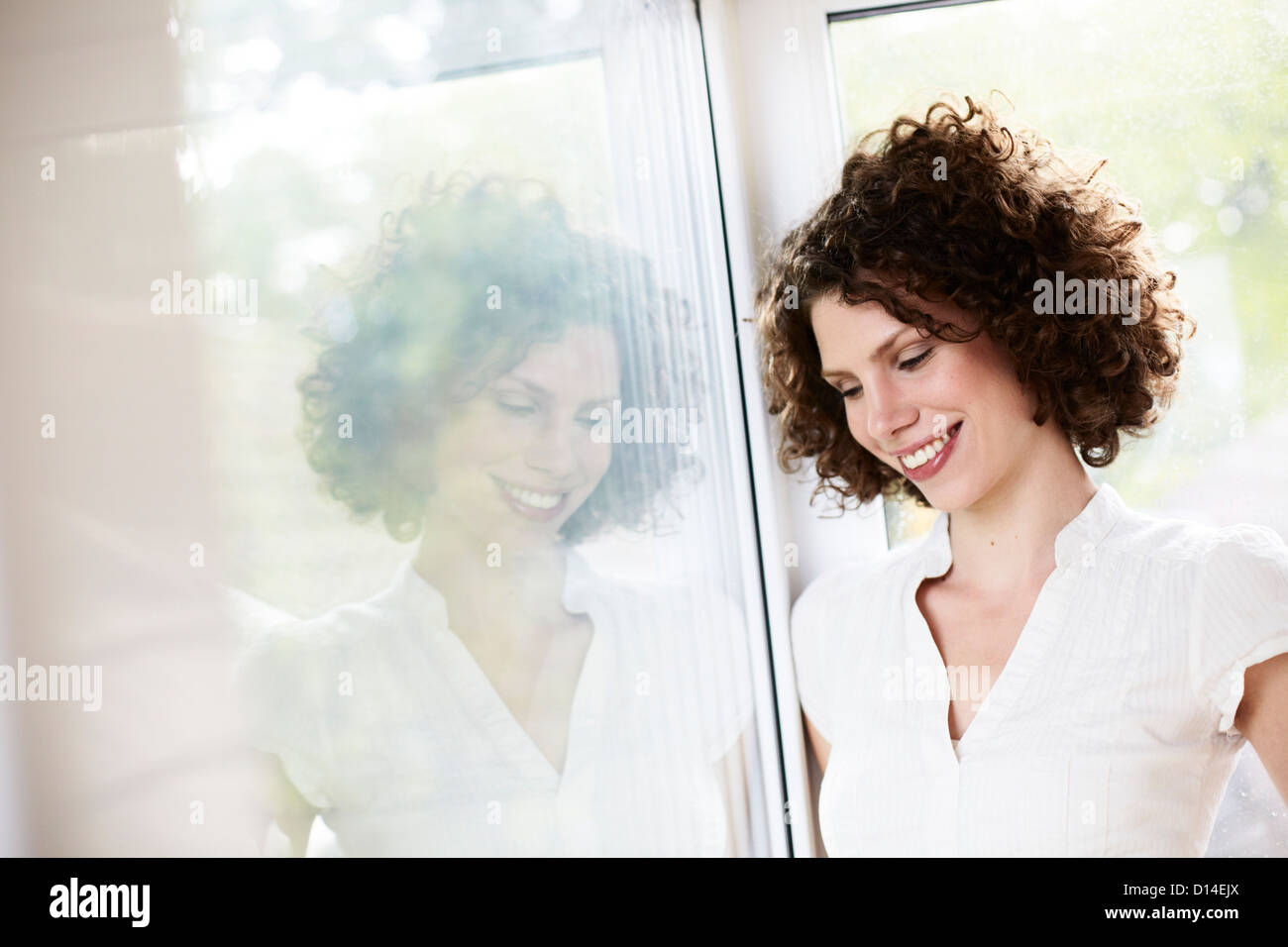 young woman standing by the window Stock Photo